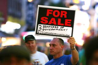A participant taking part in Occupy Las Vegas carries a sign on the Fremont Street Experience on Saturday, Oct. 15, 2011.