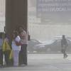 Photo: Pedestrians take cover behind a pole as high winds Photo: Pedestrians take cover behind a pole as high winds
