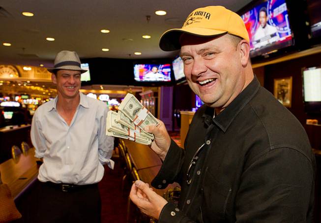 Doug O'Neill, trainer of Kentucky Derby winner I'll Have Another, displays his winnings after cashing a 200-to-1 future bet on the horse at Primm Valley Casino in Primm, Nev. Monday, June 25, 2012. O'Neill won $20,000 for his $100 bet, which he made in February, that the horse would win the Kentucky Derby. At left is Mark Verge, CEO of Santa Anita Park racetrack.