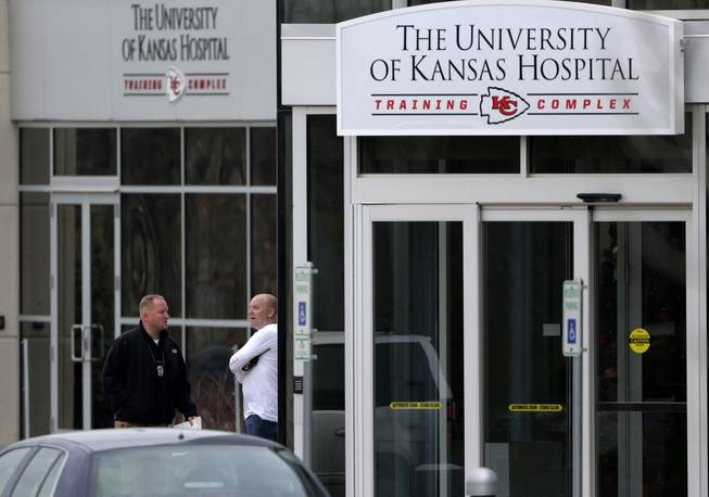A police officer, left, talks to an unidentified team official outside the training facility for the Kansas City Chiefs on Saturday, Dec. 1, 2012, in Kansas City, Mo. A Chiefs player fatally shot his girlfriend early Saturday, then drove to Arrowhead Stadium and committed suicide in front of two team officials, police said.