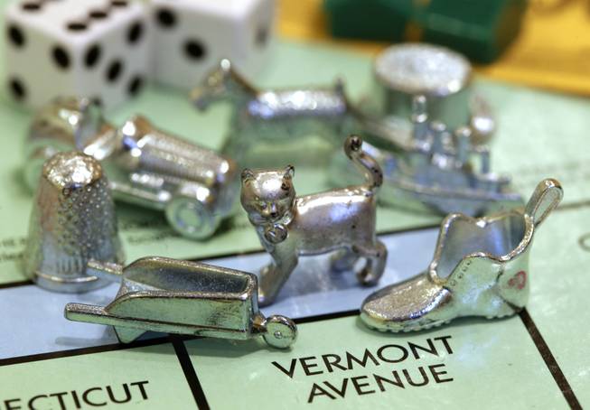 The newest Monopoly token, a cat, center, rests on a Boardwalk deed next to other tokens still in use including the wheelbarrow, left, and the shoe, right, at Hasbro Inc. headquarters, in Pawtucket, R.I., Tuesday, Feb. 5, 2013. Voting on Facebook determined that the cat would replace the iron token.