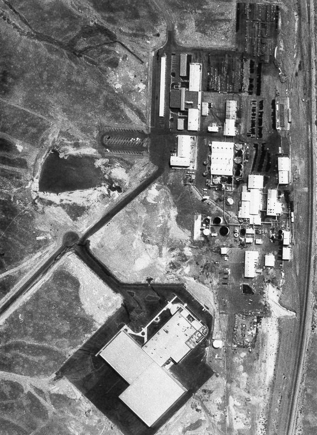 The Pacific Engineering Production Company of Nevada and Kidd plants are pictured in this September 1987 photograph. The Kidd plant is the large, flat-roofed area at the bottom of the photo. The ammonium perchlorate was stored in black barrels and aluminum tote bins.