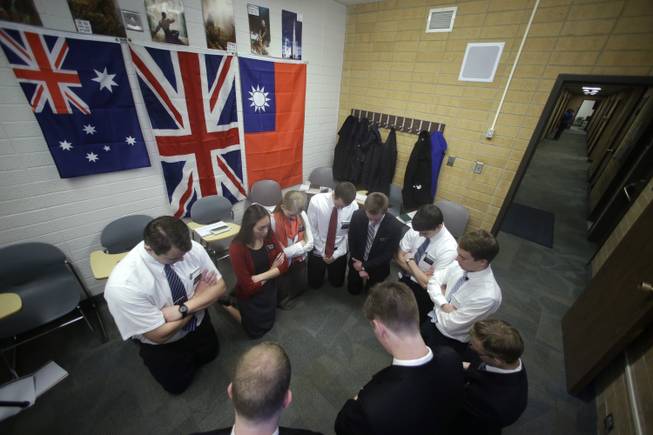 In this Jan. 8, 2013, file photo, Mormon missionaries pray before the start of a class in Mandarin Chinese language at the Missionary Training Center, in Provo, Utah. Mormon missionaries will soon spend less time knocking on doors and more time chatting online with potential converts.