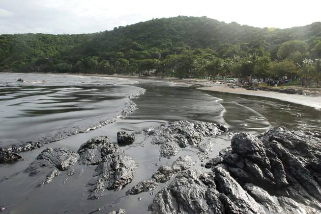 Streaks of crude oil cover the shore of Prao Bay on Samet Island in Rayong province eastern Thailand Monday, July 29, 2013. The oil spill that leaked from a pipeline has reached the popular tourist island in Thailand's eastern sea despite continuous attempts to clean it up over the weekend, officials said Monday.