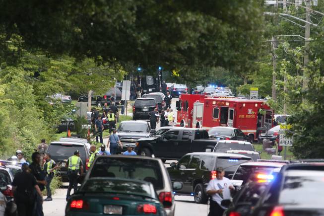 Authorities prepare at Ronald E. McNair Discovery Learning Academy after reports of a gunman entered the school, Tuesday, Aug. 20, 2013, in Decatur, Ga. A suspect was in custody after reports of gunfire at an Atlanta-area elementary school Tuesday, the school chief said, with television footage showing young students running out the school being escorted by teachers and police. Michael Thurmond told The Associated Press he had no reports of injuries and that all students and teachers are accounted for and safe. (AP Photo/Atlanta Journal-Constitution, Bob Andres)