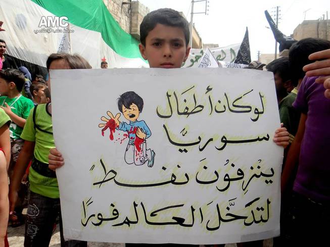 Citizen journalism image provided by Aleppo Media Center AMC which has been authenticated based on its contents and other AP reporting, shows a Syrian boy holding an Arabic placard that reads: "if Syria's children bled petrol, the entire world would have intervened," during a demonstration against the alleged chemical weapons attack at the suburbs of Damascus, in Aleppo, Syria, Wednesday, Aug. 21, 2013.