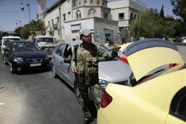 A Syrian military soldier checks the trunk of a car at a check point on Baghdad street, in Damascus, Syria, Wednesday, Aug. 21, 2013. Syrian opposition groups claimed scores have died on Wednesday in a government offensive near Damascus, attacks in which some activists say regime troops used "poisonous gas."