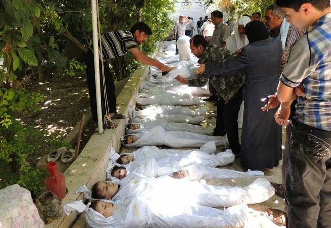 This citizen journalism image provided by the Local Committee of Arbeen which has been authenticated based on its contents and other AP reporting, shows Syrian citizens trying to identify dead bodies, after an alleged poisonous gas attack fired by regime forces, according to activists in Arbeen town, Damascus, Syria, Wednesday, Aug. 21, 2013.
