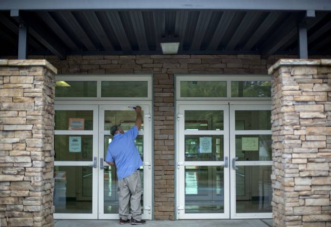 Carpenter William Brooks secures a piece of plexiglass to the front door of the Ronald E. McNair Discovery Learning Academy where a glass panel was shot out during an exchange of gunfire Tuesday between police and a man who entered the school with an assault rifle, Wednesday, Aug. 21, 2013, in Decatur, Ga.