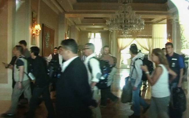 In this image made from video, U.N. weapon inspectors, seen through window, walk through the hotel lobby upon their arrival at a hotel in Damascus, Syria, Sunday, Aug. 18, 2013. A team of U.N. weapons inspectors arrived in Damascus on Sunday for a long-delayed mission to investigate the alleged use of chemical arms in Syria's civil war.