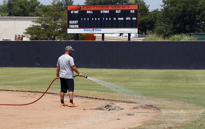 A worker waters the edge of the infield at the baseball field at East Central University in Ada, Okla., Wednesday, Aug. 21, 2013. Australian Christopher Lane, who was on a baseball scholarship at East Central University was in Duncan, Okla., visiting his girlfriend, when he was shot and killed.