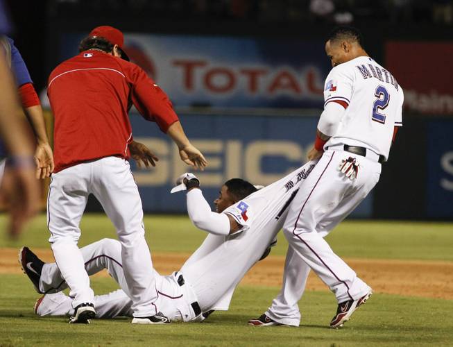 Texas Rangers' Elvis Andrus is dragged on the field by Leonys Martin (2) and Derek Holland, left, after hitting the game-winning sacrifice fly, scoring Adam Rosales, against the Houston Astros during the ninth inning of a baseball game, Wednesday, Aug. 21, 2013, in Arlington, Texas. The Rangers won 5-4.