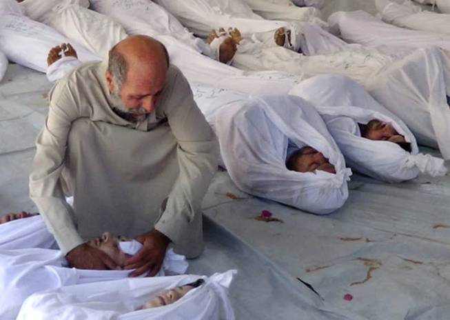 This citizen journalism image provided by the Media Office Of Douma City which has been authenticated based on its contents and other AP reporting, shows a Syrian man mourning over a dead body after an alleged poisonous gas attack fired by regime forces, according to activists, in Douma town, Damascus, Syria, Wednesday, Aug. 21, 2013.