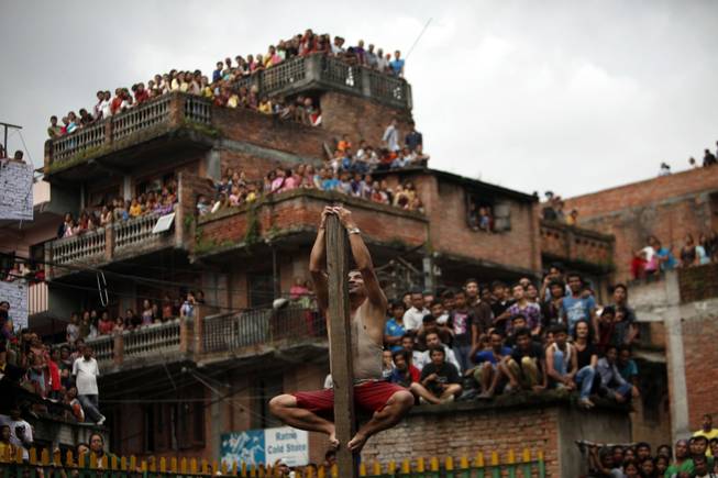 A Nepalese climbs a pole erected in a pond as part of Deopokhari festival in Katmandu, Nepal, Friday, Aug. 23, 2013. The festival is held to appease, what locals believe, a demon in the pond. Every year on this day cattle is sacrificed to the pond demon so that no human lives are lost drowning in the pond, a common occurrence before the festival began, according to locals.