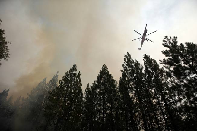 A helicopter drops water over a hot spot while battling the Rim Fire near Yosemite National Park, Calif., on Sunday, Aug. 25, 2013. With winds gusting to 50 mph on Sierra mountain ridges and flames jumping from treetop to treetop, hundreds of firefighters have been deployed to protect this and other communities in the path of the Rim Fire raging north of Yosemite National Park.