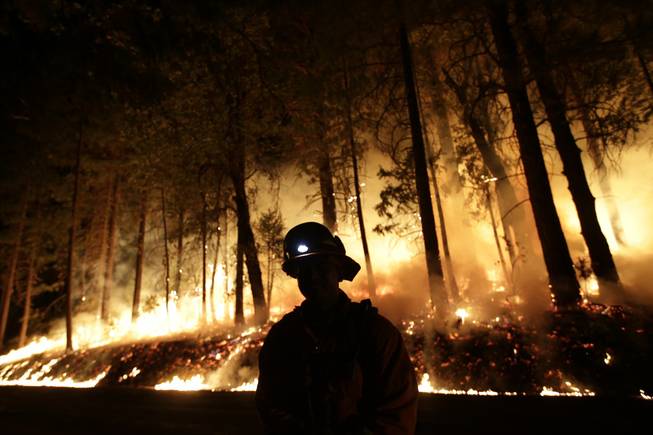 A firefighter watches for spot fires during a burnout operation while battling the Rim Fire near Yosemite National Park, Calif., on Sunday, Aug. 25, 2013. Fire crews are clearing brush and setting sprinklers to protect two groves of giant sequoias as a massive week-old wildfire rages along the remote northwest edge of Yosemite National Park.