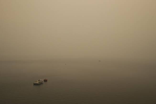 A small boat floats on the Hetch Hetchy Reservoir as the smoke and some embers from the Rim Fire fill the air in Yosemite National Park, Calif., on Sunday, Aug. 25, 2013. With winds gusting to 50 mph on Sierra mountain ridges and flames jumping from treetop to treetop, hundreds of firefighters have been deployed to protect this and other communities in the path of the Rim Fire raging north of Yosemite National Park.