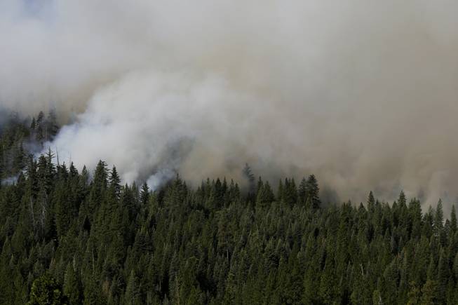 A smoke rises from the Rim Fire near Yosemite National Park, Calif., on Sunday, Aug. 25, 2013. With winds gusting to 50 mph on Sierra mountain ridges and flames jumping from treetop to treetop, hundreds of firefighters have been deployed to protect this and other communities in the path of the Rim Fire raging north of Yosemite National Park.