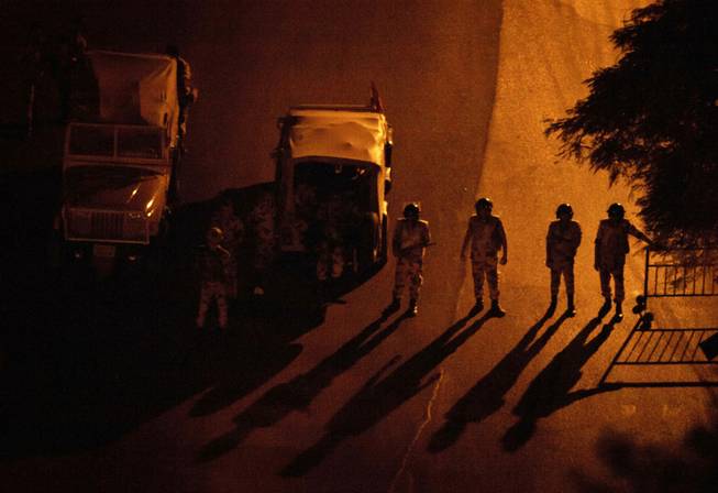 In this Aug. 20, 2013 file photo, Egyptian soldiers stand guard at a checkpoint during a dawn-to-dusk curfew in the Zamalek district of Cairo, Egypt. The curfew has been a shock to Cairo, a city where cafes stay packed into the night and parents routinely take their children out for dinners nearing midnight. The military-backed government’s curfew, after violent unrest following the July 3 coup that ousted President Mohammed Morsi, slashed the typical Cairo 24-hour life to just 11 hours.