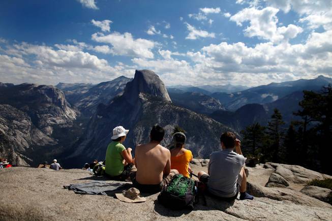 Tourists enjoy the view at Glacier Point in California's Yosemite National Park on August 27, 2013, as the Rim fire continues to rage about 25 miles away. As the devastating fire spreads deeper into Yosemite, would-be park visitors are having to decide whether to cancel plans made months or years in advance or press ahead with a visit that could potentially end in a smoky evacuation. Many are choosing to keep their date with El Capitan and Half Dome.