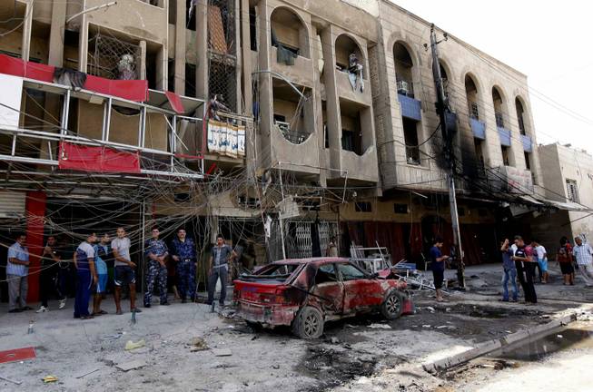 People inspect the scene of a car bomb attack in the Sha'ab neighborhood of Baghdad, Iraq, Wednesday, Aug. 28, 2013. A coordinated wave of bombings tore through Shiite Muslim areas in and around the Iraqi capital early Wednesday, killing scores and wounding many more, officials said. The blasts, which came in quick succession, targeted residents out shopping and on their way to work.