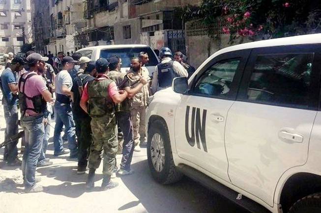 In this citizen journalism image provided by the United media office of Arbeen which has been authenticated based on its contents and other AP reporting, Syrian rebels escorted the UN investigation team, in Damascus countryside of Zamalka, Syria, Wednesday, Aug. 28, 2013.