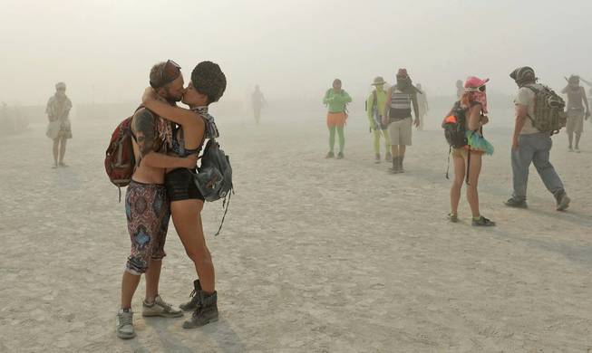 In this Wednesday, Aug. 28, 2013 photo, a couple kisses at Burning Man in Gerlach, Nev. Once a year, tens of thousands of participants gather in Nevada's Black Rock Desert to create Black Rock City, dedicated to community, art, self-expression and self-reliance.