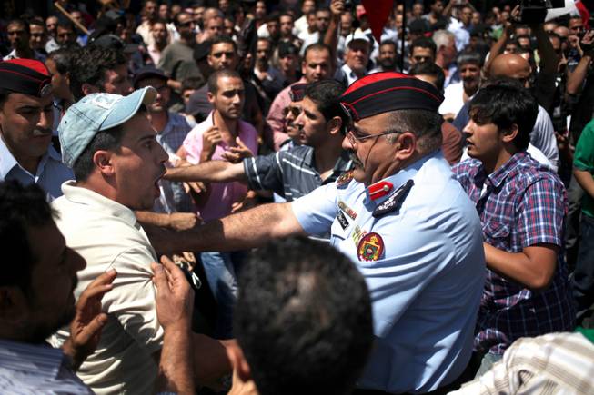 A Jordanian man, left, chants anti-President Bashar Assad slogans as a police officer pushes him away to separate him from opposing protesters from the Jordanian Communist Party and other leftist groups against any American military strike against Damascus, in Amman, Jordan, Friday, Aug. 30, 2013.