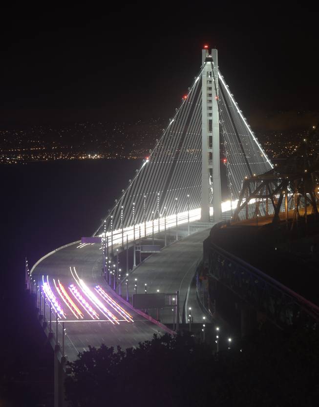 In this Monday, Sept. 2, 2013 photo taken in a long exposure and provided by the Bay Area Toll Authority, police vehicles open the San Francisco-Oakland Bay Bridge to traffic, in San Francisco. At the modest inaugural ceremony, the new, self-anchored suspension bridge with its single white tower was praised as a dramatic safety upgrade over its predecessor and a beautiful example of public art.