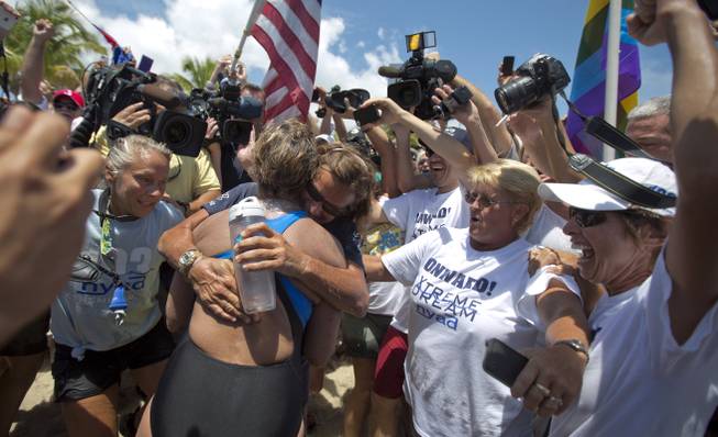 As fans cheer for long distance swimmer Diana Nyad, right, her trainer Bonnie Stoll hugs her, after swimming from Cuba,Monday, Sept. 2, 2013. Looking dazed and sunburned, U.S. endurance swimmer Diana Nyad walks ashore becoming the first person to swim from Cuba to Florida without the help of a shark cage. Nyad arrived at the beach just before 2 p.m. EDT, about 53 hours after she began her swim in Havana on Saturday.