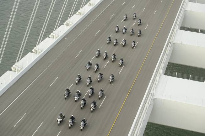 In this photo taken on Monday, Sept. 2, 2013, provided by the Bay Area Toll Authority, a phalanx of police officers lead a procession across the San Francisco-Oakland Bay Bridge to mark the east span's opening in San Francisco. At the modest inaugural ceremony, the new, self-anchored suspension bridge with its looming, single white tower was praised as a dramatic safety upgrade over its predecessor. It also was held up as a beautiful example of public art.