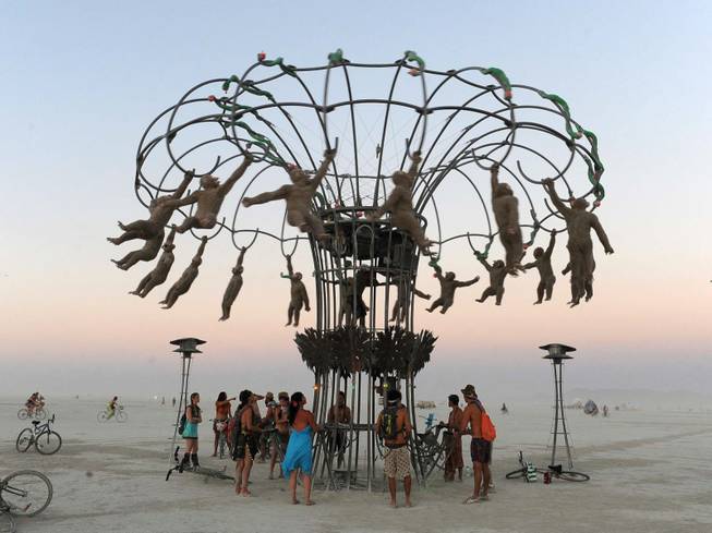 People bang on drums to make monkey effigies spin in an interactive sculpture at the Burning Man festival in Gerlach, Nev. on Friday, Aug. 30, 2013. Once a year, tens of thousands of participants gather in Nevada's Black Rock Desert for the counterculture event.