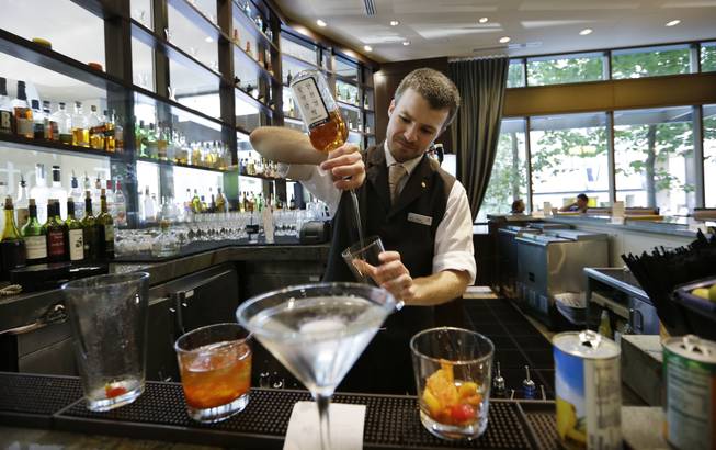 In this July 3, 2013, photo, bartender Derek Simoes mixes drinks in the newly-redesigned bar during "social hour" at a Sheraton hotel in Seattle. Long treated as dead spaces that hotel guests raced through on the way to the elevator, lobbies are being transformed into places to work, surf the Web or meet friends for a drink.