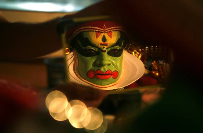 In this Wednesday, Sept .4, 2013 photo, an Indian Kathakali artist is reflected on a mirror as he dons make up prior to a performance in Chennai, India. Kathakali is a classical dance that was created in the ancient kingdoms that now make up Kerala, a state on India's southwestern coast some 400 years back. The roots are in Sanskrit temple theater, which, like Japan's Kabuki or Hollywood's silent films, had a glossary of hand gestures and exaggerated movements of the facial muscles to express emotion. Dancers are swathed in robes and yards and yards of petticoat, encrusted with ribbons, tassels and embroidery, ropes of brass chain and plastic beads.