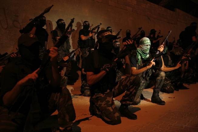 Masked Palestinian members of the "Ezz Al-Din Al Qassam" militia, the military wing of Hamas, hold their weapons and pose for the media during a march on the streets of Gaza City, Wednesday, Sept. 4, 2013. Arabic on headband reads, "No God but Allah and Mohammed is his prophet, Ezz Al-Din Al Qassam brigade."