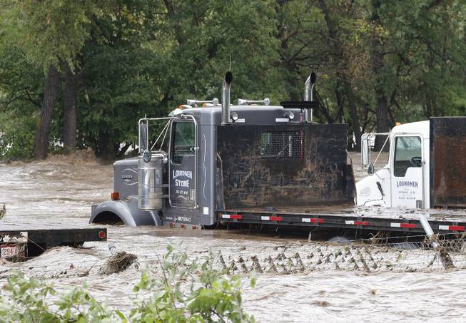 The overflowing St. Vrain River swamps parked semi trucks following overnight flash flooding, one mile east of Lyons, Colo., Thursday, Sept 12, 2013. The widespread high waters are keeping search and rescue teams from reaching stranded residents in Lyons and nearby mountain communities as heavy rains hammered northern Colorado.