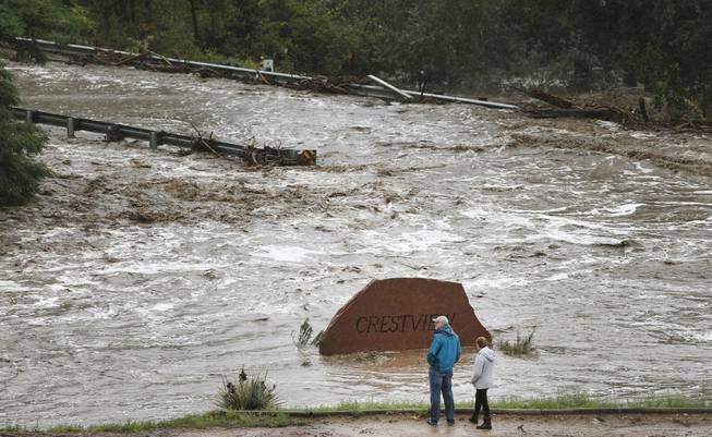 Local residents look over a road washed out by a torrent of water following overnight flash flooding near Left Hand Canyon, south of Lyons, Colo., Thursday, Sept 12, 2013. The widespread high waters are keeping search and rescue teams from reaching stranded residents in Lyons and nearby mountain communities as heavy rains hammered northern Colorado.