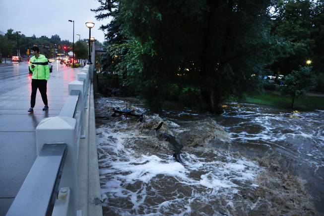 A man walks past dangerously high Boulder Creek following overnight flash flooding in downtown Boulder, Colo., Thursday, Sept 12, 2013. Flash flooding in Colorado has left two people dead and the widespread high waters are keeping search and rescue teams from reaching stranded residents and motorists in Boulder and nearby mountain communities as heavy rains hammered northern Colorado.