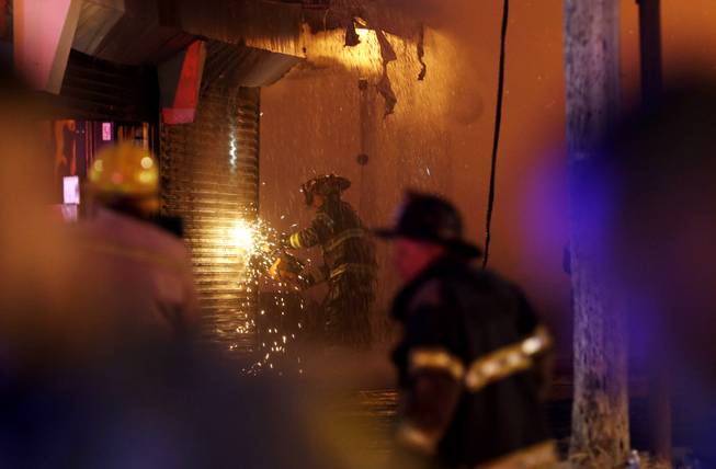 A firefighter saws through a metal wall on a building while battling a fire at the Seaside Park boardwalk on Thursday, Sept. 12, 2013, in Seaside Park, N.J. The fire began in a frozen custard stand on the Seaside Park section of the boardwalk and quickly spread north into neighboring Seaside Heights.
