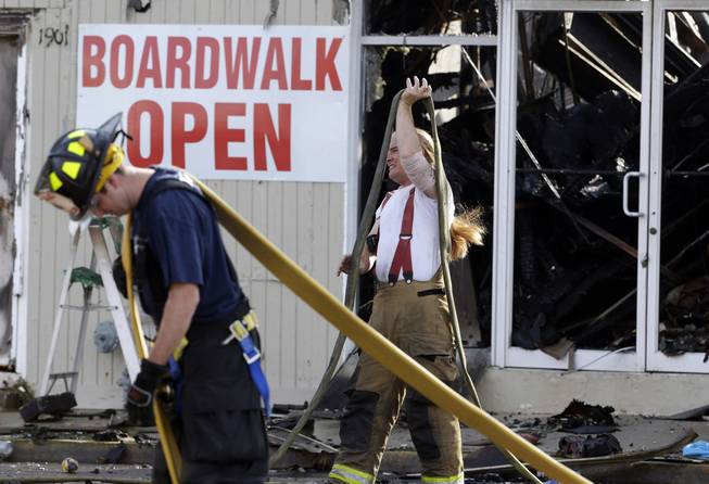 Firefighters arrange hoses the morning after a massive fire burned a large portion of the Seaside Park boardwalk, Friday, Sept. 13, 2013, in Seaside Park, N.J. The fire, which apparently started in an ice cream shop and spread several blocks, hit the recently repaired boardwalk, which was damaged last year by Superstorm Sandy.