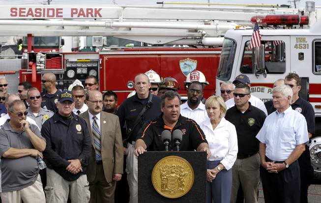 New Jersey Gov. Chris Christie, center, talks during a news conference, the morning after a massive fire burned a large portion of the Seaside Park boardwalk, Friday, Sept. 13, 2013, in Seaside Park, N.J. The fire, which apparently started in an ice cream shop and spread several blocks, hit the recently repaired boardwalk, which was damaged last year by Superstorm Sandy. There were no reports of any injuries.