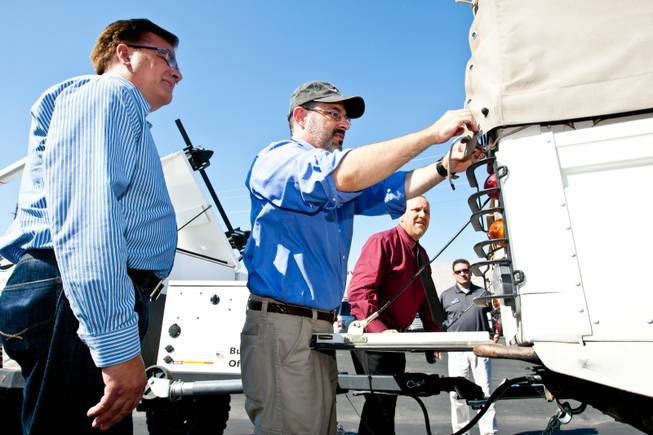 Reporter Matt Hufman practices tying the roof in place during a mechanical demonstration of the 1997 Land Rover Defender he and Mike Smith, left, will drive exploring Nevada over the next year working on the Finding Nevada Project at the Land Rover Las Vegas dealership Friday, September 13, 2013. Land Rover employees, from right, Mark Padilla and Rick Nelson participate in the vehicle instruction.