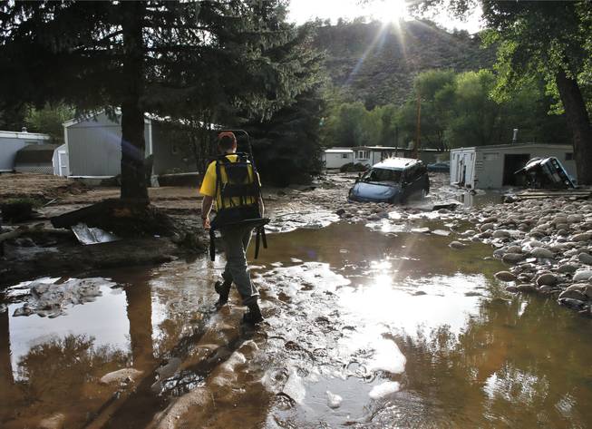 Ben Rodman walks while helping a friend salvage her home after floods left homes and infrastructure in a shambles in Lyons, Colo., on Friday, Sept. 13, 2013. Days of heavy rains and flash floods that washed out the town's bridges and destroyed the electrical and sanitation infrastructure have left many Lyons residents stranded with minimal access to help.