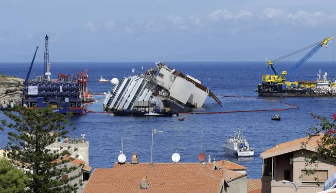 The Costa Concordia ship lies on its side on the Tuscan Island of Giglio, Italy, Monday, Sept. 16, 2013. An international team of engineers is trying a never-before attempted strategy to set upright the luxury liner, which capsized after striking a reef in 2012 killing 32 people.