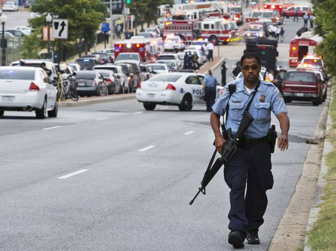 A Metropolitan Police Department officer walks near the Washington Navy Yard after at least one gunman launched an attack inside the Washington Navy Yard, spraying gunfire on office workers in the cafeteria and in the hallways at the heavily secured military installation in the heart of the nation's capital, in Washington, on Monday, Sept. 16, 2013.