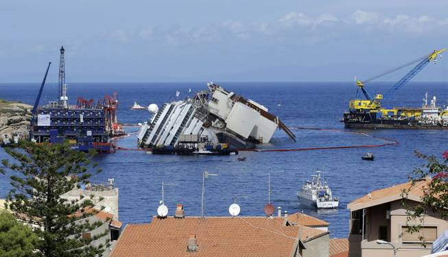 The Costa Concordia ship lies on its side on the Tuscan Island of Giglio, Italy, Monday, Sept. 16, 2013. An international team of engineers is trying a never-before attempted strategy to set upright the luxury liner, which capsized after striking a reef in 2012 killing 32 people.