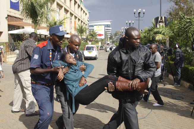 Saturday, Sept. 21, 2013: Nairobi, Kenya_ A security officer helps a wounded woman outside the Westgate Mall after gunmen opened fire and threw grenades. Kenyan authorities said Islamic extremist attackers remain inside the upscale Kenyan shopping mall Sunday, holding an unknown number of hostages, after killing and injuring scores of people the attack.