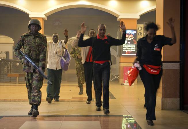 Saturday, Sept. 21, 2013: Nairobi, Kenya_Civilians who had been hiding during a gun battle hold their hands in the air as a precautionary measure before being searched by armed police leading them to safety, inside the Westgate Mall. Kenyan authorities said Islamic extremist attackers remain inside the upscale Kenyan shopping mall Sunday, holding an unknown number of hostages, after killing and injuring scores of people in the attack.