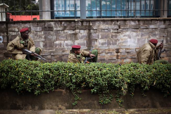 Kenya security forces are seen behind a wall outside the Westgate Mall in Nairobi, Kenya Monday morning, Sept. 23, 2013. Kenya's military launched a major operation at the upscale Nairobi mall and said it had rescued "most" of the hostages being held captive by al-Qaida-linked militants during the standoff that killed at least 68 people and injured 175.