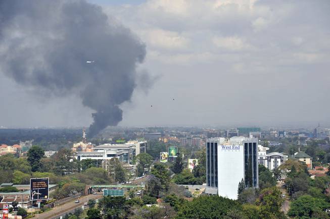 A helicopte and birds fly above as a plume of black smoke billows rising over the Westgate Mall, following large explosions and heavy gunfire, in Nairobi, Kenya Monday, Sept. 23, 2013. Four large blasts rocked Kenya's Westgate Mall on Monday, sending large plumes of smoke over an upscale suburb as Kenyan military forces sought to rescue an unknown number of hostages held by al-Qaida-linked militants.